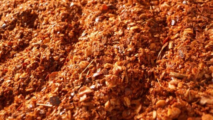 Intensely vibrant, ground chili showcases a fiery blend of crushed flakes and seeds. Its coarse texture, with diverse particle sizes, embodies its potent spiciness and rich flavor.
