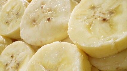 A mesmerizing close-up captures the creamy allure of sliced bananas. Each uniform piece unveils a soft, buttery texture, adorned with delicate brown speckles amidst its gentle yellow hue.
