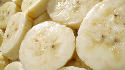 Dive into the sensory embrace of sliced bananas: soft, yielding to the touch, a buttery yellow canvas marred by gentle, caramel-brown flecks, whispering promises of sweet indulgence.
