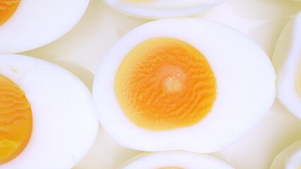 Behold a close-up scene of boiled eggs, meticulously sliced to reveal their pristine whites and rich orange yolks. An elegant arrangement showcases the tantalizing interplay of textures and hues.
