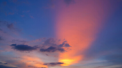 Obraz premium A stunning sunset with vibrant pink and orange rays spreading across the sky, contrasting beautifully with the blue and purple hues. Dark clouds add depth to this mesmerizing scene. 