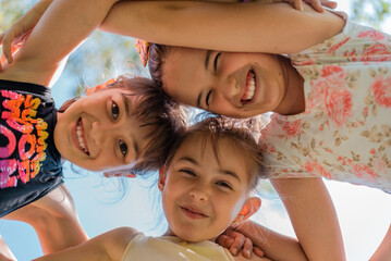 Happy children embracing each other having fun and smiling at camera, group of joyful kids playing together outside.