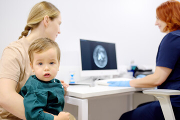 Toddler boy with his mom are at appointment with a pediatric neurologist. A mother tells an attentive doctor about her baby's injury.