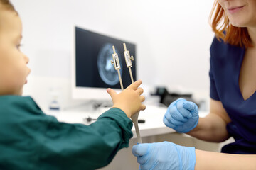 Baby and his mother are being seen by a pediatric neurologist in medical clinic. Doctor conducts tests, checks the reflexes, hearing of small patient using tuning fork. Highly qualified cure
