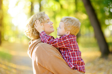 Close-up portrait of a mother and son during a walk in the autumn park. Woman holds her toddler son...