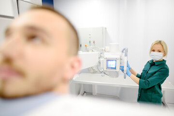 Female radiologist is making an Xray of lungs of patient in X-ray room of modern clinic. Doctor performs a fluorography. Medical examination of people is prevention of tuberculosis spread