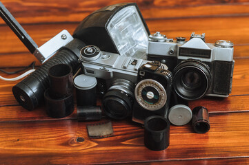 A set of rare photographic equipment. Camera, flash, film and exposure meter on a wooden...