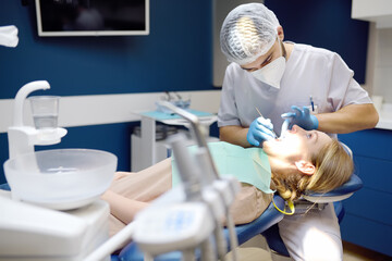 Dentist and patient at modern medical center. Doctor treats a young woman teeth in hospital....