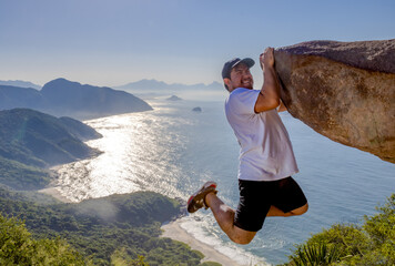 Adventurous climber hangs off Pedra do Telégrafo with breathtaking coastal view in Rio de Janeiro
