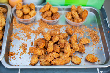 Several pieces of fried chicken nuggets are placed on a tray.