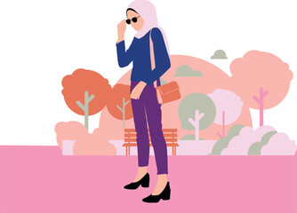 The hijabi girl is standing in the park.