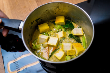 Chef at the kitchen preparing green curry with herbs and rice