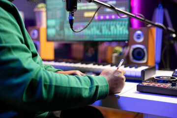 Musician taking notes on paper to produce a new track, making rhymes and blending musical elements...