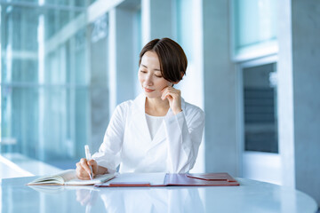 室内で書類を確認する白衣を着た女性