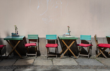 Red and green wooden chairs and tables at a small outdoor cafe/bar.