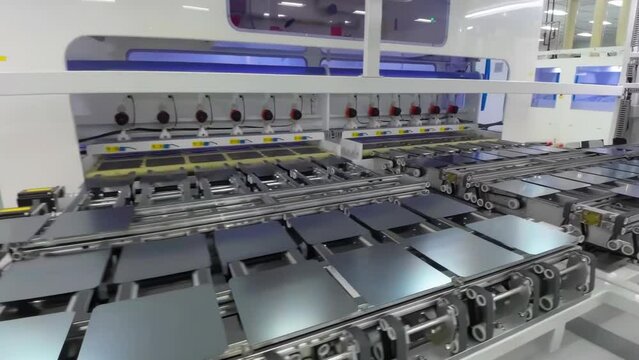 Automated solar panels being moved by robot arms on conveyor belts during high tech production process in renewable energy factory, Photovoltaic cells being placed on assembly lines.