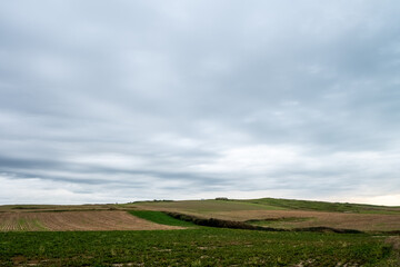 Obraz premium A rural scene with farmland under a cloudy sky, showcasing the beauty of nature and agriculture in a serene setting