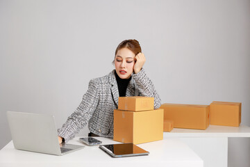 Asian smart entrepreneur business woman in casual suit surround by parcel boxes using computer...