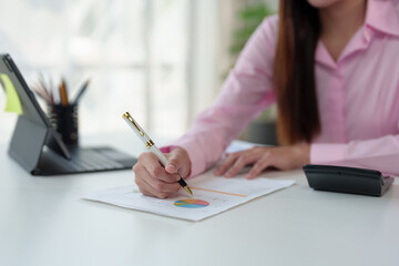 Asian businesswoman sitting at work desk filing financial documents using laptop computer doing taxes, online finance, online presentation in modern company startup business idea.