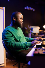 Artist playing piano electronic keyboard and recording new sounds, producing new midi controller notes in his home studio. Audio producer working with digital audio workstation software.