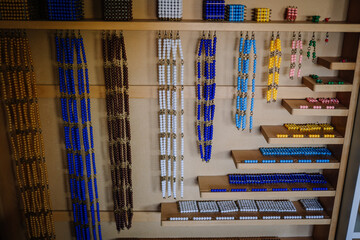Obraz premium Valmiera, Latvia - May, 22, 2024 - Montessori beads of various colors and lengths arranged on shelves in a classroom. The beads are used for educational counting and math activities.