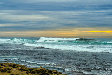 2023-12-31 VIEW OF THE PACIFIC OCEAN FROM THE SHORES OF THE LA JOLLA COASTLINE WITH A BEAUTIFUL SKY AND SUNSET WITH WAVES COMING ON SHORE NEAR SAN DIEGO CALIFORNIA-