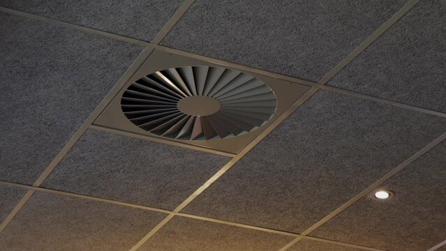 A contemporary ceiling fan set into a textured drop ceiling, highlighting modern office design and efficient air circulation features. Modern Ceiling Fan Integrated Into Textured Ceiling at Office