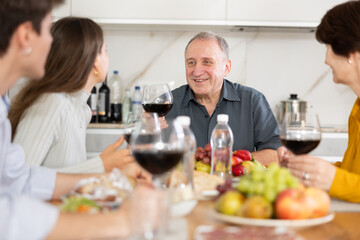 Calm smiling aged man enjoying family dinner with wife, adult daughter and friendly son-in-law,...