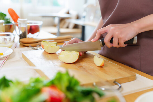 Closeup hands of asian women using knife to cutting slices apple on cutting board to preparing fruits and fresh vegetables of ingredient for cooking breakfast meal while making healthy food lifestyle