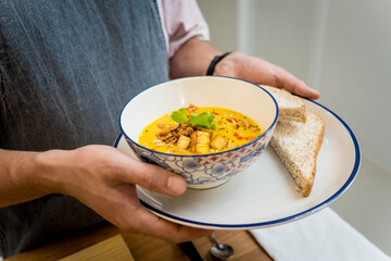 A bowl of pumpkin porridge with tofu and vegetables
