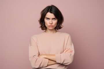 Fototapeta premium A woman with a pink sweater is looking down and crossing her arms