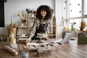 Female artist sculpting clay in creative studio. Woman engaged in pottery making, surrounded by...