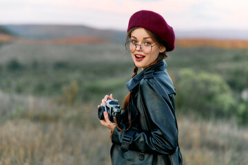 Stylish woman in red beret and glasses capturing the beauty of nature with her camera in the field