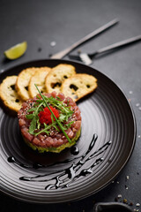 Tuna and avocado tartare on a dark ceramic plate