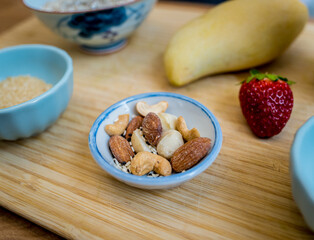 Cutting board with ingredients for preparing bowl of oats with strawberries and mango