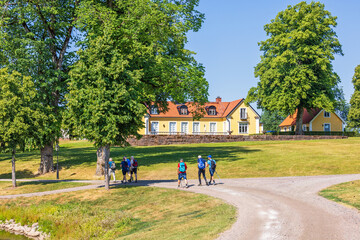 People walking on a road by a country house a sunny summer day