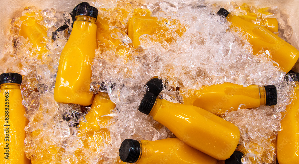 Sticker freshly squeezed juices in plastic bottles in ice at the market