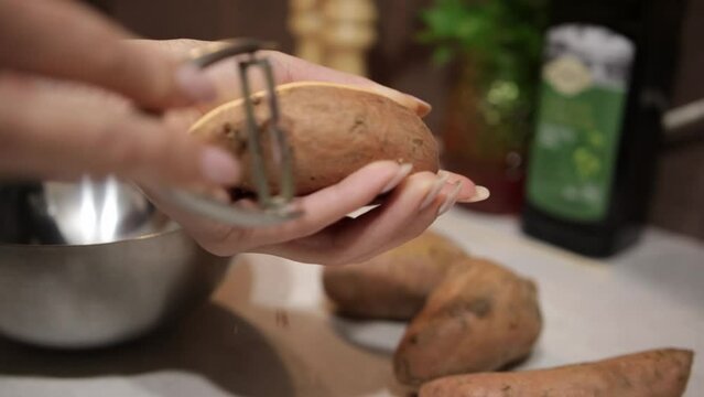 Female Hands Peeling Peruvian Ground Apple Using Peeler. closeup, slow motion