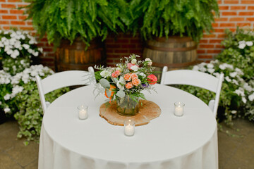 A table with a white tablecloth with candles and a bouquet of flowers