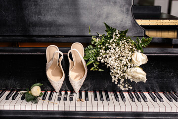 Wedding shoes, rings, and bouquet displayed on a piano keyboard