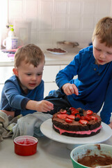 Siblings decorate a homemade cake with fresh berries