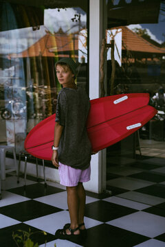 Portrait of young happy stylish woman with surfboard.