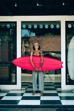 Portrait of young happy stylish woman with surfboard.
