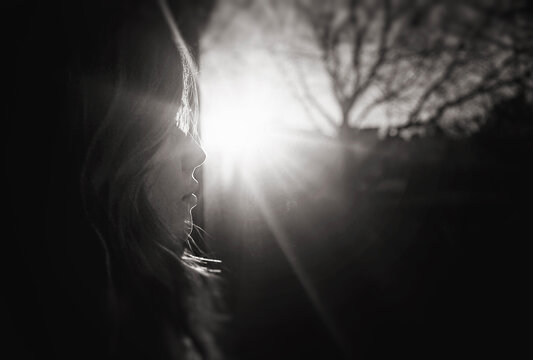 Profile of beautiful young girl looking out sunny window