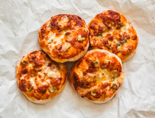 Mini pizza with ham, olives and mozzarella - a delicious snack, tapas on a light background, top view