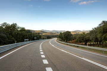Fototapeta premium Curves of an empty road entering nature, on the way to nowhere