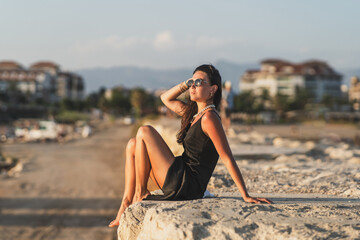 Woman in black dress, sitting on rock