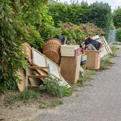 Pile of bulky waste on the side of the road with wooden furniture, drawers, laundry basket and...