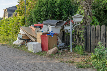 Pile of bulky waste on the side of the road with wooden furniture, drawers and laundry basket