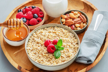 Bowl of porridge or oatmeal with different ingredients on wooden tray. Breakfast serving.